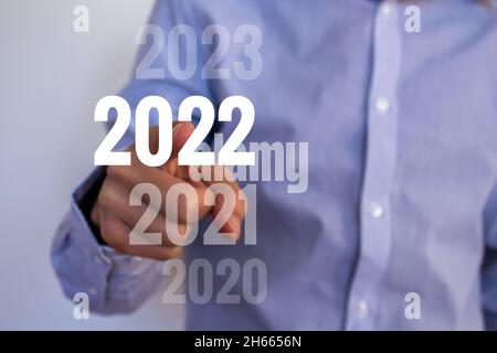 Geschäftsmann wählt das Jahr 2022. Neues Jahr 2022 kommt Konzept. Hand zeigt 2022.