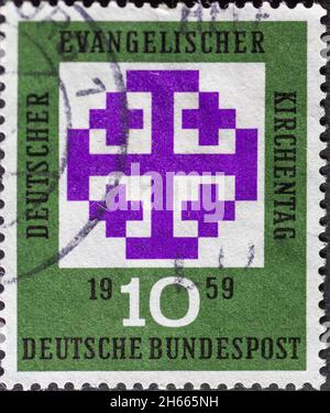 DEUTSCHLAND - UM 1959: Diese in Deutschland gedruckte Briefmarke in grün zeigt das Jerusalemkreuz in Purpur, das Symbol der Deutschen Evangelischen Kirche Stockfoto