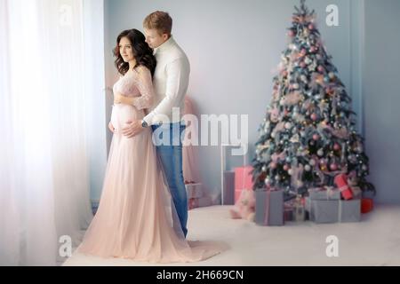 Junge glückliche verheiratete Paar am Neujahr. Tauschen Sie Weihnachtsgeschenke und Umarmung. Stockfoto