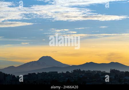 Vulkan Cayambe bei Sonnenaufgang mit Quito City Silhouette, Ecuador. Stockfoto