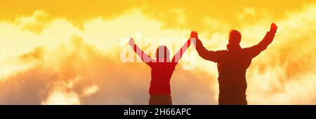 Glückliche Gewinner erreichen Lebensziel - Erfolg Menschen auf dem Gipfel. Geschäftserfolgekonzept. Zwei Personen verbinden sich in den Wolken mit den Armen in der Luft Stockfoto