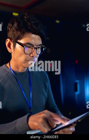 Männlicher Ingenieur aus Asien, der im Computerserverraum ein digitales Tablet verwendet Stockfoto
