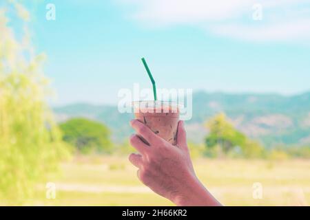 Hand halten Eis Latte Kaffee in einem hohen Glas. Kalten Sommer trinken Hintergrund Stockfoto