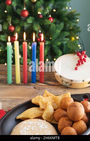 Tag Bei Kerzenschein. Typisch kolumbianisches Essen. Buñuelo, Pudding und Flocken mit Kerzen und Weihnachtsbaum im Hintergrund. Traditioneller kolumbianischer Urlaub. Stockfoto