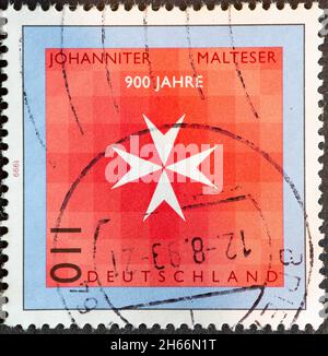 DEUTSCHLAND - UM 1999: Eine Briefmarke aus Deutschland, die das Wappen der Johanniter für 900 Jahre Johanniter und Maltese zeigt Stockfoto