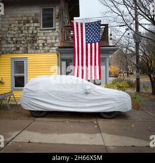 American Veteran's Day und Bundesfeiertage zeigen eine große US-Flagge über einem Auto mit Schutzhülle. Veterans Day, Waffenstillstandstag ist Th Stockfoto