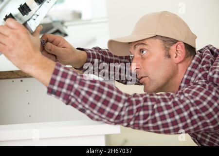 Mann installiert Induktionskochfeld in einer Küche Stockfoto