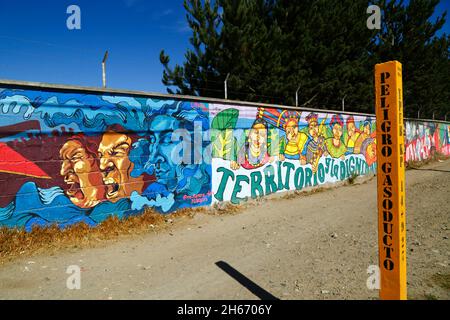 Senkata, El Alto, Bolivien. November 2021. Wandmalereien an der Wand außerhalb der Senkata-Brennstofffabrik und eine Post, die auf das Vorhandensein einer unterirdischen Gaspipeline hinweist. Das Massaker von Senkata fand hier am 19. November 2019 während der Gewalt nach den umstrittenen Präsidentschaftswahlen vom 20. Oktober 2019 statt. Bei gewalttätigen Zusammenstößen zwischen Sicherheitskräften und Anhängern des ehemaligen Präsidenten Evo Morales (der am 10. November zurückgetreten war), der das Werk blockiert hatte, starben mindestens 8 Zivilisten. Stockfoto