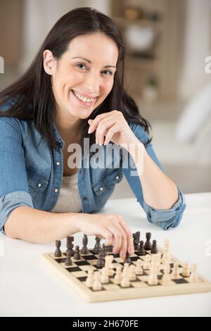 Frau lächelt, während sie beim Schach einen Schritt macht Stockfoto