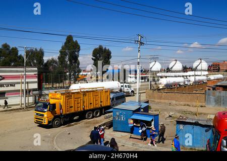 Senkata, El Alto, Bolivien. November 2021. Tankwagen für Flüssiggas und ein Lieferwagen für Inlandsflaschen (gelb) vor der Senkata-Brennstofffabrik auf der Av 6 de Marzo / Camino Oruro in El Alto. Yacimientos Petrolíferos Fiscales Bolivianos (YPFB, Boliviens staatliches Öl- und Gasunternehmen) verfügt hier über eine große Raffinerie- und Speicheranlage, Die La Paz, El Alto und die Umgebung mit Benzin, Diesel und flüssigem Erdgas (in Flaschen für den Hausgebrauch, aber auch für Fahrzeuge und andere Industrien) versorgt. Im Hintergrund sind einige der sphärischen Gasspeichertanks zu sehen. Stockfoto