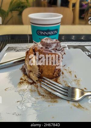 Sankt Petersburg, Russland - 21. Juni 2021. Eine Einweg-Tasse mit Tee und dem Cinnabon-Kuchen begann und endete, Gabel und Messer, auf dem Tisch Stockfoto