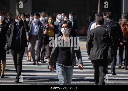 Tokio, Japan. Oktober 2021. Fußgänger mit Gesichtsmasken überqueren während der Mittagspause in der Nähe des Bahnhofs Tokio die Straße. Kredit: SOPA Images Limited/Alamy Live Nachrichten Stockfoto