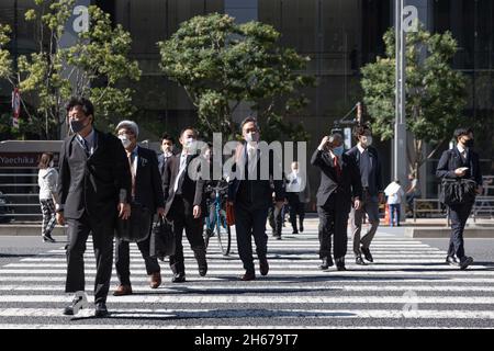 Tokio, Japan. Oktober 2021. Fußgänger mit Gesichtsmasken überqueren während der Mittagspause in der Nähe des Bahnhofs Tokio die Straße. Kredit: SOPA Images Limited/Alamy Live Nachrichten Stockfoto