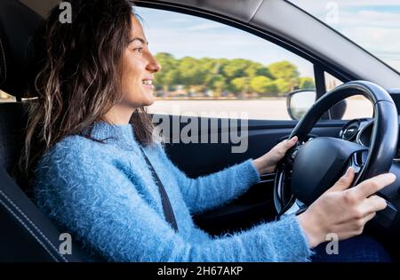 Junge Frau fährt Auto auf der Straße. Führerschein und Fahrsicherheitskonzept. Stockfoto