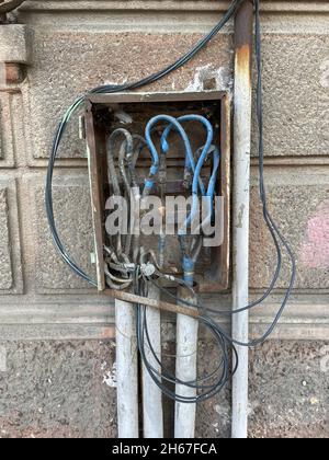 Elektrische Schalttafel für den Außenbereich mit nach außen ragenden Drähten, gefährlich hohe Spannung. Unprofessionelle Arbeit eines Elektrikers. Stockfoto