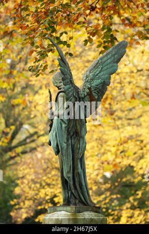 Engelsfigur mit ausgebreiteten Flügeln auf einem Herbstfriedhof Stockfoto