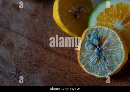 Halb schimmelige Zitrone und frische Limette schneiden sich auf einem hölzernen Schneidebrett zusammen Stockfoto