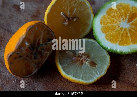 Halb schimmelige Zitrone und frische Limette schneiden sich auf einem hölzernen Schneidebrett zusammen Stockfoto