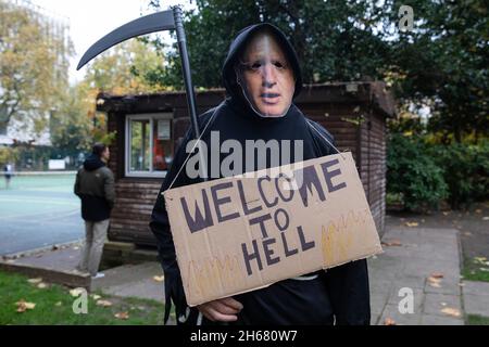 London, Großbritannien. November 2021. Ein Klimaaktivist der Extinction Rebellion, der als Grim Reaper verkleidet ist und eine Boris Johnson Maske trägt, bereitet sich darauf vor, an einem marsch des Aufstandes und der Rebellion teilzunehmen, der anlässlich des Endes und des erwarteten Scheiterns des Klimagipfels der COP26 organisiert wird. Aktivisten wollten eine Botschaft an die britische Regierung senden, dass die Proteste fortgesetzt werden, um dringende Maßnahmen zur Bekämpfung der Klima- und ökologischen Notlage zu gewährleisten. Kredit: Mark Kerrison/Alamy Live Nachrichten Stockfoto