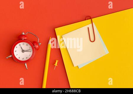Roter Wecker und Haftnotizen mit Platz für Text auf rotem Hintergrund Stockfoto