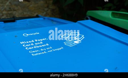 Ein blauer Papierrecycling-Abfallbehälter in einem Garten mit Anweisungen auf dem Deckel Stockfoto