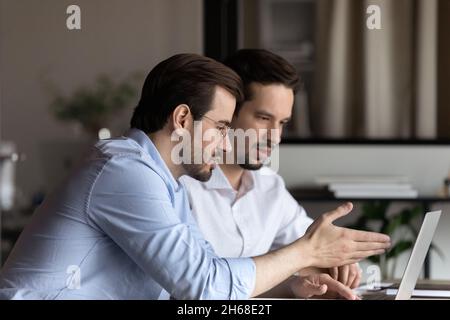 Konzentrierte junge gemischte Rennkollegen, die am Computer zusammenarbeiten. Stockfoto