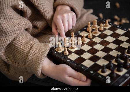 Frau, die Schachfiguren auf ein Schachbrett legt. Stockfoto