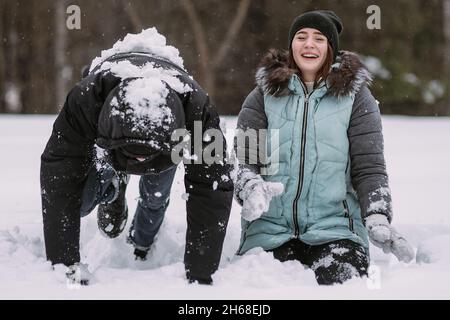 Glückliches Paar von Teenagern, die Spaß beim Spielen im Schnee im Winterwald haben Stockfoto