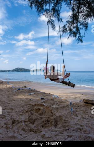 Bang Tao Beach Phuket Thailand, Strand mit Palmen und ein paar Männer und Frauen in der Schaukel am Strand. Sommer, Reisen, Urlaub und Urlaub Konzept - Swing hängt von Kokospalme Stockfoto