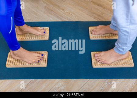 Nahaufnahme der Füße eines Paares, die mit scharfen Nägeln auf Sahu-Brettern stehen. Yoga-Übungskonzept. Stockfoto