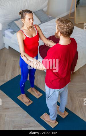 Paar, das mit scharfen Nägeln auf Sahu-Brettern steht - Mann, der seine Frau unterstützt. Yoga gemeinsam üben. Stockfoto