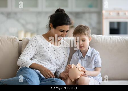 Glückliche Mutter lehrt kleinen Sohn, Geld zu sparen Stockfoto