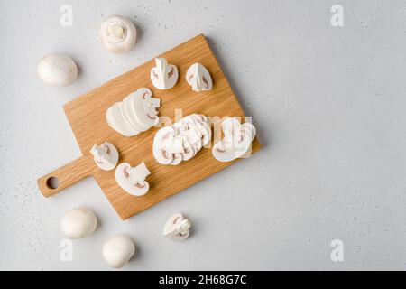 Roher leckerer frischer weißer Champignon auf Holzhackbrett. Vegetarisches Rezept. Zutaten zum Kochen. Geschnittene portobello-Pilze auf hellem Hintergrund Stockfoto