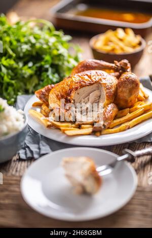 Gebratenes Hähnchen auf einer Gabel mit Beilagen, Reis und pommes frites. Stockfoto