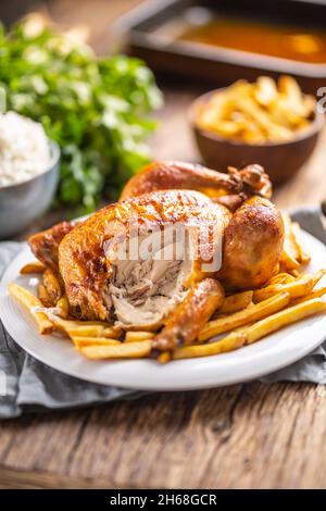Sehr lecker gebratenes Hähnchen ganz auf einem Teller und Holztisch. Stockfoto