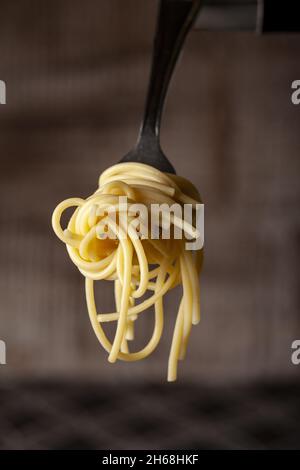 Eine vertikale Aufnahme von einfachen gekochten leckeren Spaghetti-Nudeln auf einer Gabel Stockfoto