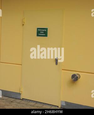 Eine vertikale Aufnahme eines Notausgangsschildes in deutscher Sprache an einer gelben Tür Stockfoto