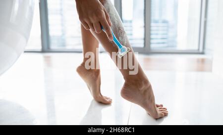 Junge unkenntliche Frau mit Rasiermesser rasieren Beine. Stockfoto