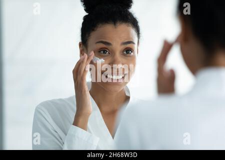 Glücklich schöne junge afrikanische Frau Anwendung Creme. Stockfoto