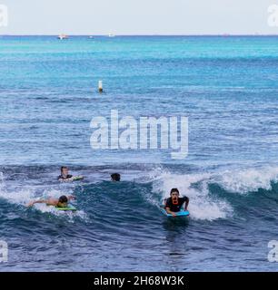 Honolulu, Hawaii - 6. Nov 2021-Junge Jungen spielen auf ihren Boogey Boards im Surf. Stockfoto