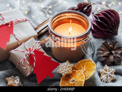 Adventsdekoration und Geschenkschachteln mit brennenden Kerzen. Weihnachten Hintergrund Stockfoto