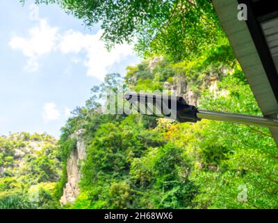 Solarleuchte. Moderne elektrische Leistung führte Glühbirne hängen auf der Stange unter dem Dach des Gebäudes auf grünen Natur Berg und blauen Himmel Hintergrund. Stockfoto