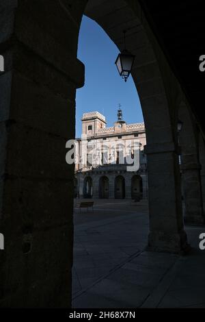 Blick auf das Rathaus von Avila in einem Rahmen der Silhouette eines architektonischen Bogens und Säulen der Plaza del Mercado Chico in Avila, Spanien. Stockfoto