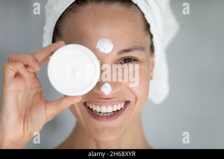 Glückliche tausendjährige lateinische hispanische Frau, die Creme auf das Gesicht auftragen. Stockfoto