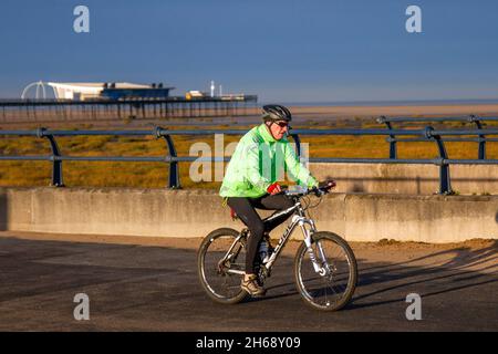 Southport, Merseyside. UK Wetter 14 Nov 2021. Sonniger, aber kalter Start in den Tag im nordwestlichen Badeort. Die Anwohner nutzen den hellen Start, um an der Strandpromenade leichte Übungen zu genießen. Kredit; MediaWorldImages/AlamyLiveNews Stockfoto