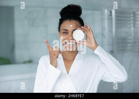 Happy schöne junge afrikanische Frau Anwendung feuchtigkeitsspendende Creme. Stockfoto