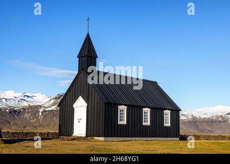 Diese Schwarze Kirche aus dem 19. Jahrhundert ist eine der ältesten Holzkirchen Islands. Budir, Halbinsel Snaefellsnes. Herbstfarben mit schneebedeckten Bergen Stockfoto