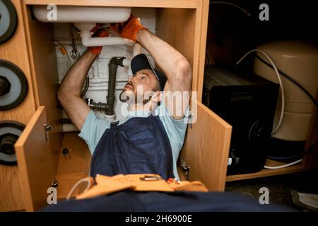 Männlicher Klempner repariert Spülrohr in der Küche Stockfoto