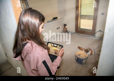 Junges Mädchen platziert Objekt in Augmented Reality mit einem Tablet. Umzug in ein neues Zuhause Stockfoto