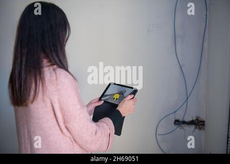 Frau, die ein Objekt mit einem Tablet in Augmented Reality platziert. Umzug in ein neues Zuhause Stockfoto